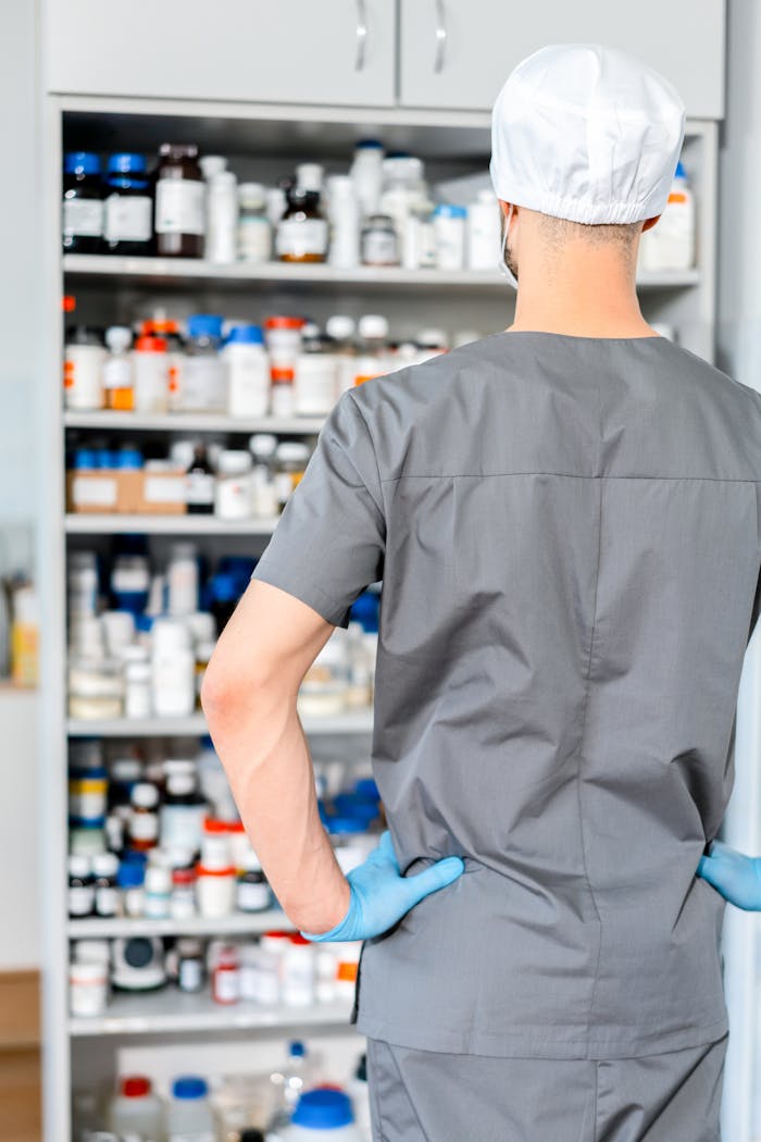Back View of a Pharmacist Standing in front of a Cabinet Full of Medication